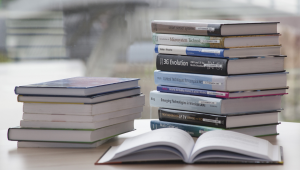 stack of books on table with one book opened