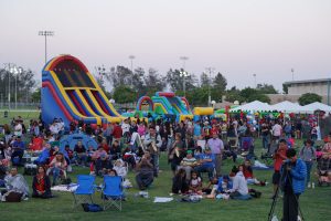 A crowd of people sit on grass at event