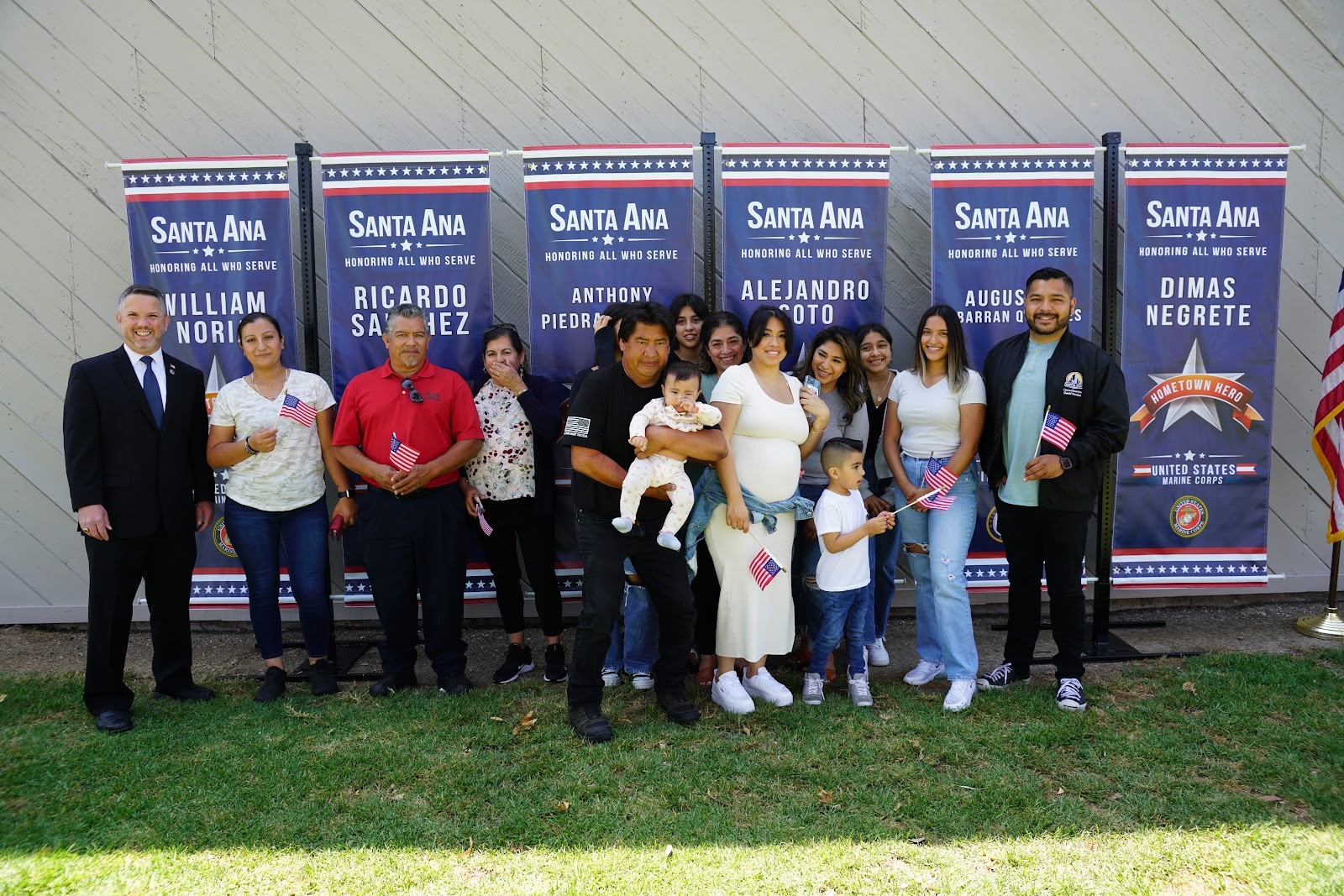 Families and dignitaries posing in front of hometown heroes banners