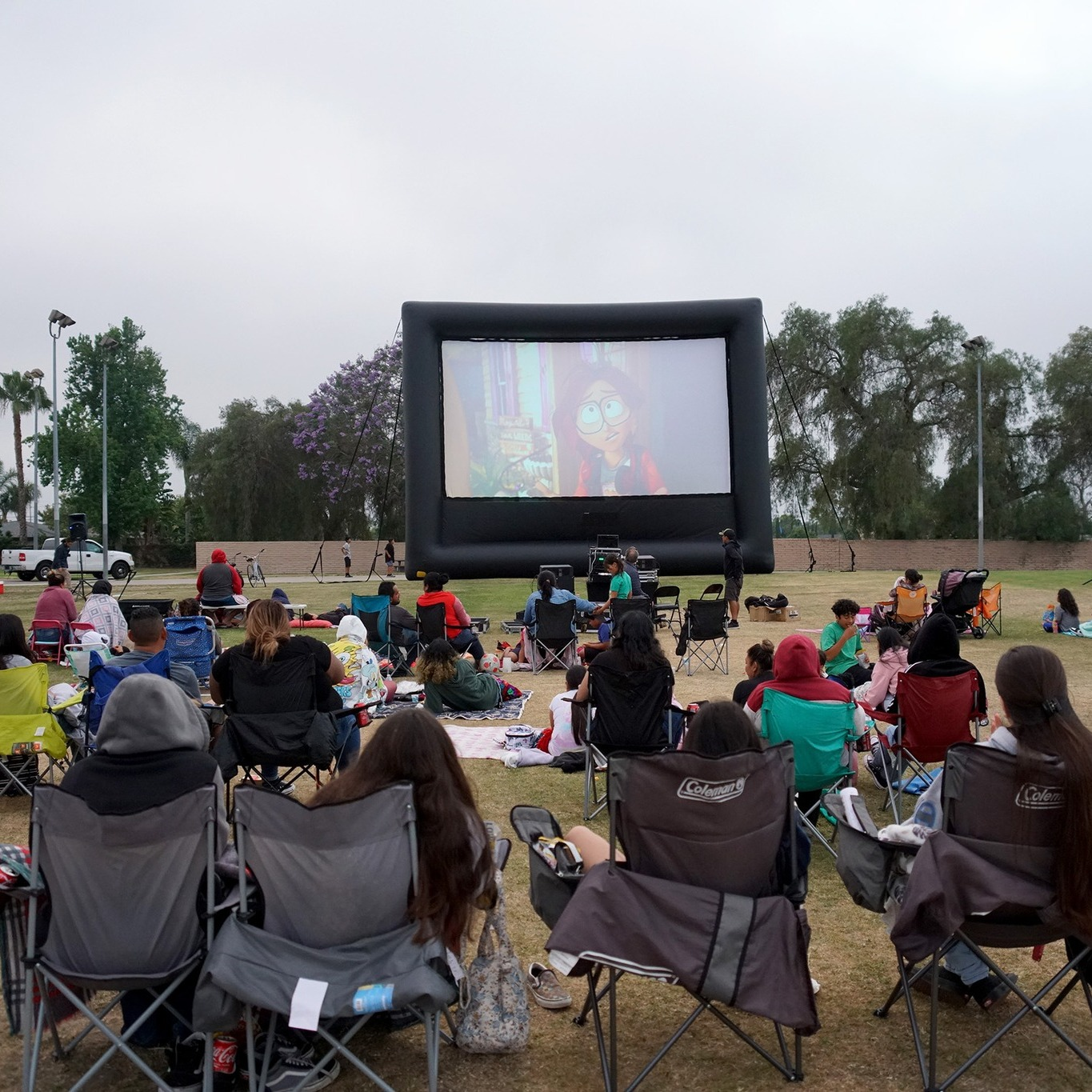 Crowd watching a movie on an inflatable screen at a park