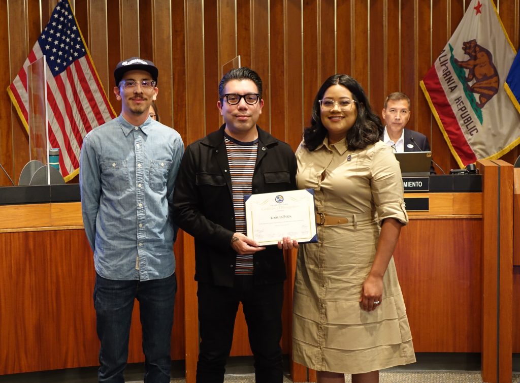 Councilmember Lopez recognizes the owners of Loosie's Pizza at a City Council meeting