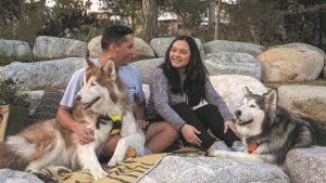 two adults with two dogs sitting on rocks