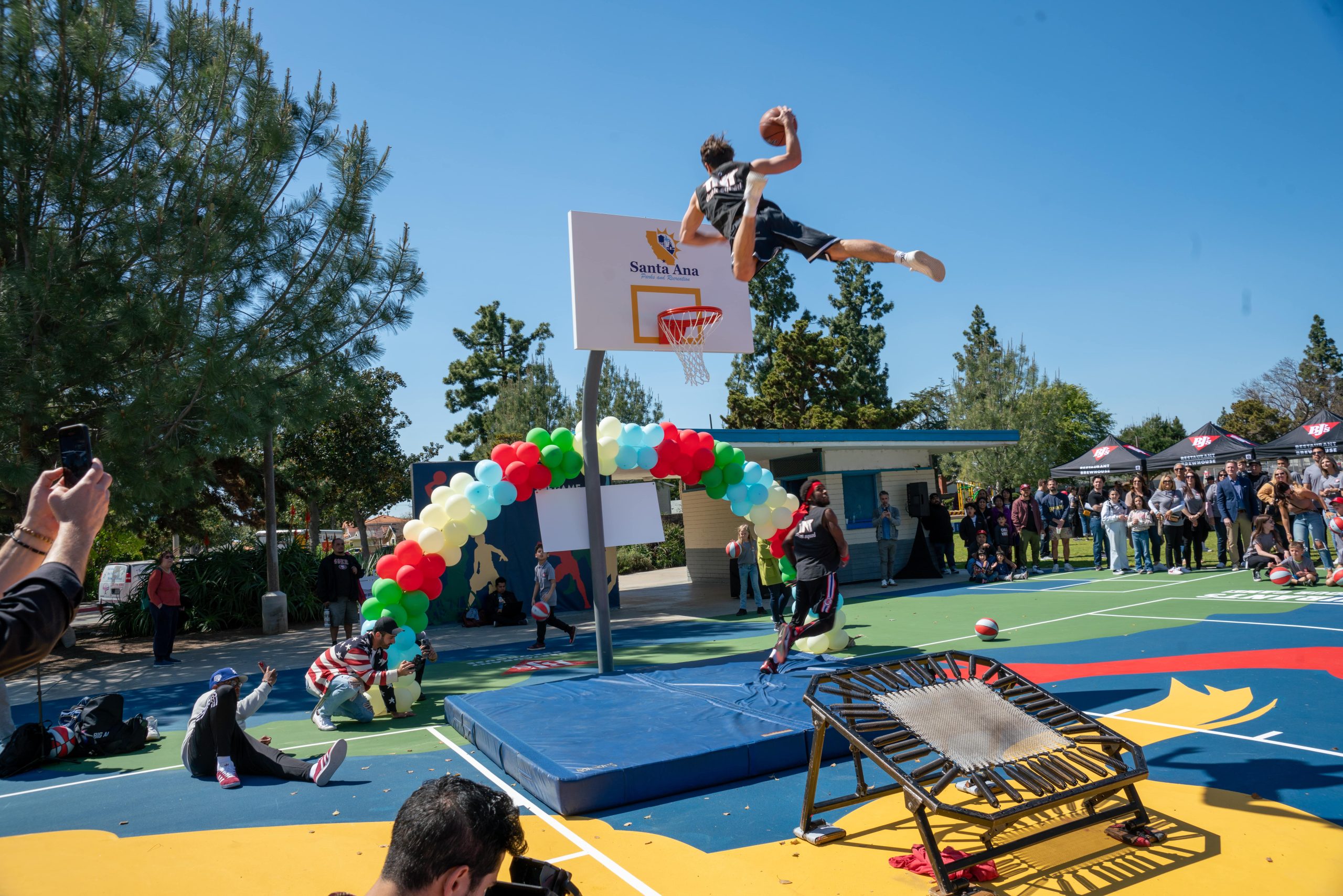 A man jumping off a trampoline attempting a slam dunk at Portola Park