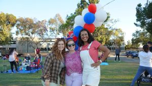 three individuals with red, white, and blue balloons