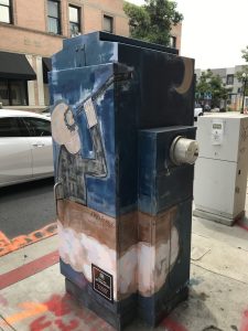 Utility box with art of a night scene and skeleton man looking at the moon