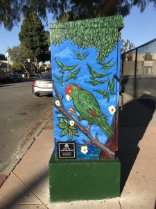 Utility box with the art of a flock of green parrots amongst a blue background