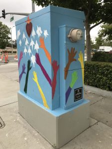 Utility box with art of hands of different colors reaching for a heart