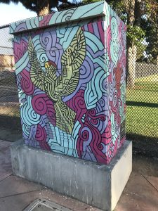 Utility box with art of a green parrot and shades of blue patterns