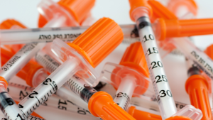 A pile of orange and white syringes.