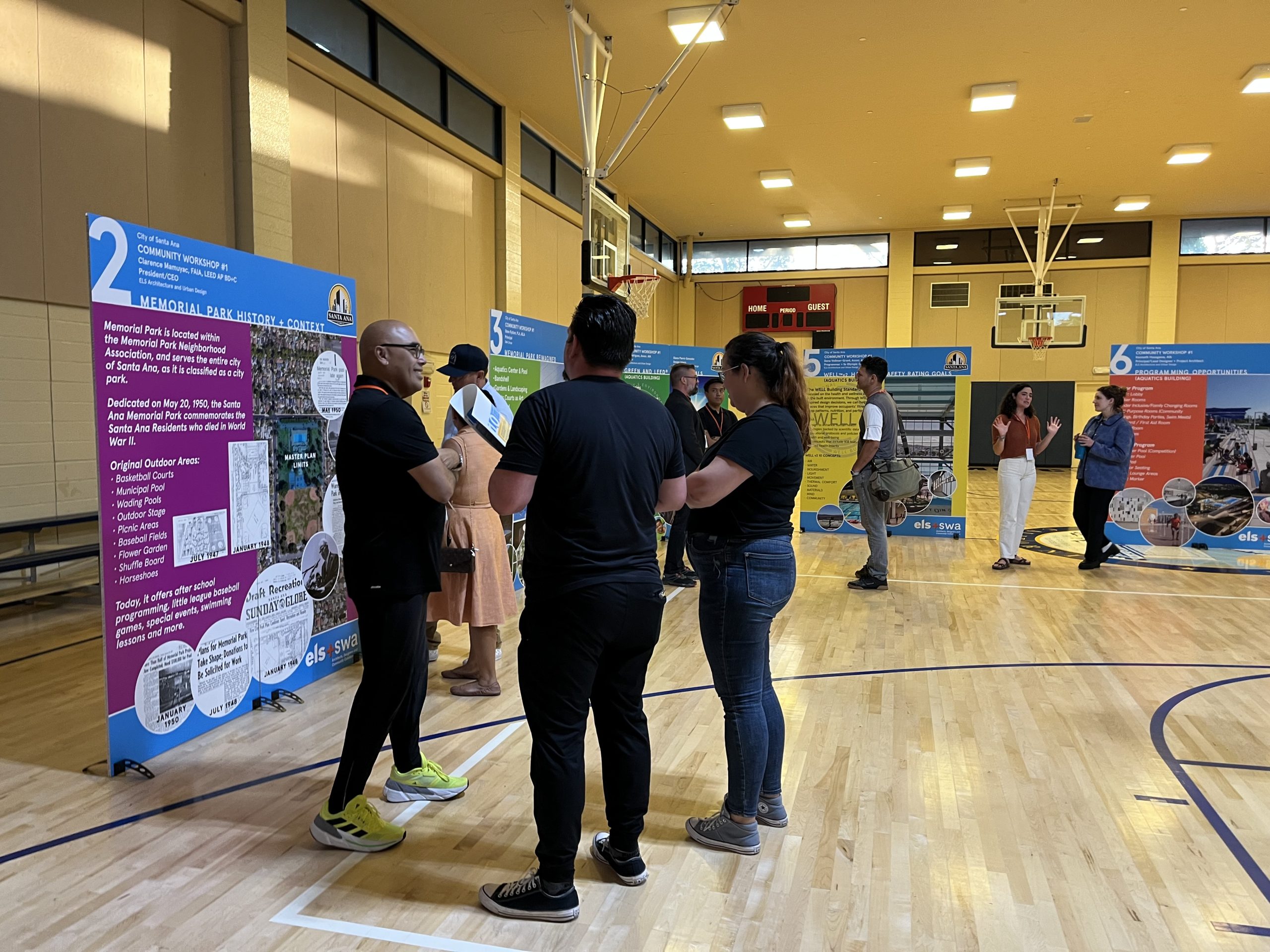 People stand in a gymnasium looking at large displays with information.