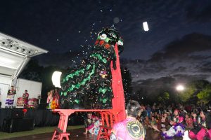 A person in a lion dance costume performs for a crowd of people.