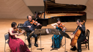 people in a circle playing violins and a cello