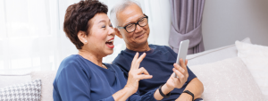 older asian couple on couch talking to phone