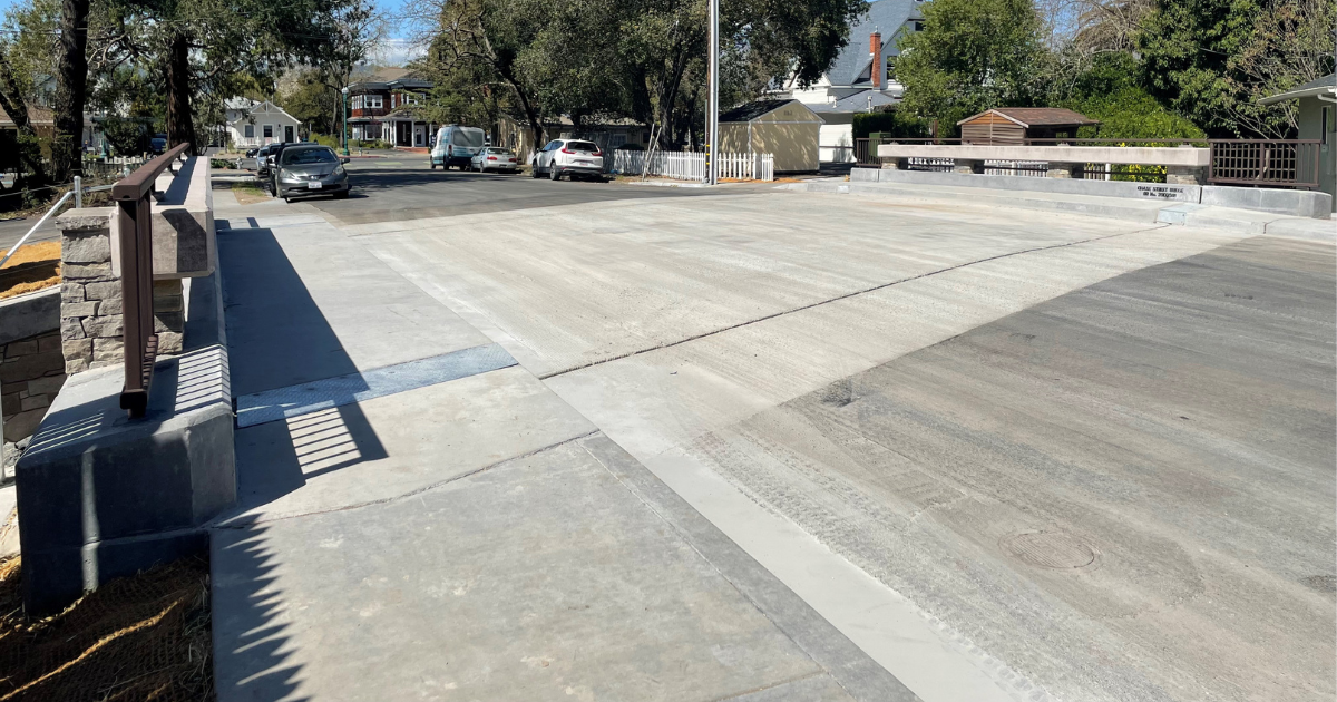 a two lane bridge with side walks over a small creek.