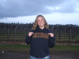 Photo of Teagan Rhodes wearing a Michigan Sweatshirt with a vineyard view behind her.