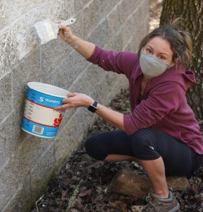 Volunteer Stephanie White helps paint over graffiti in Mountain Cemetery