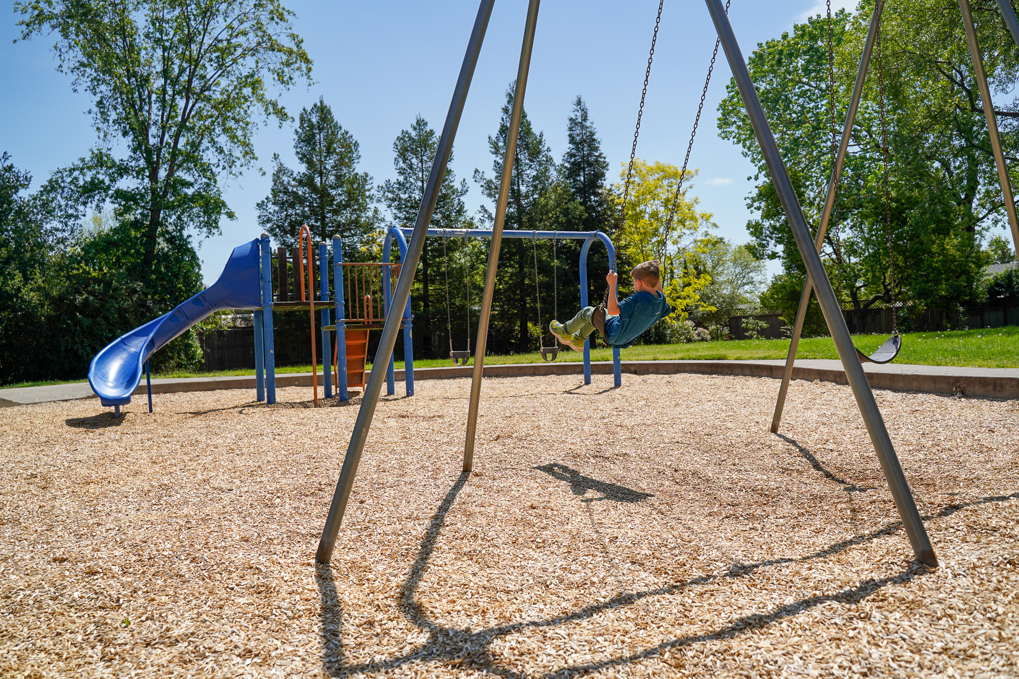 Child on a swing at a playground in a park.