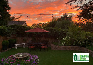 Photo of colorful sunset with garden and artificial turf and patio furniture.