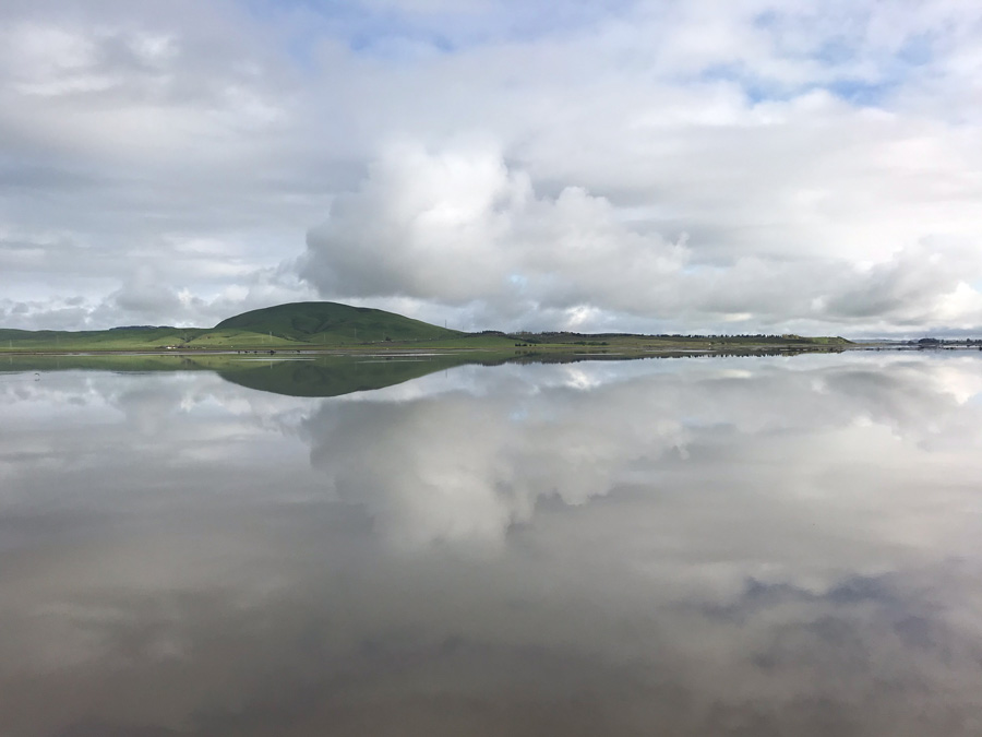 View of bay reflecting sky and clouds.