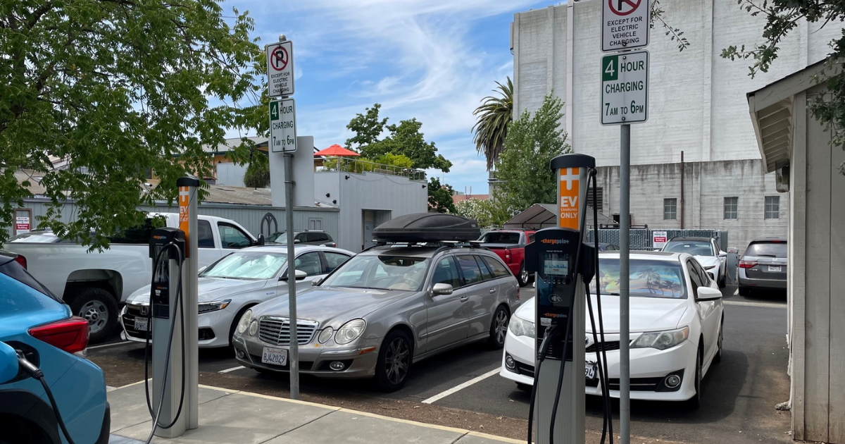 Two electric vehicle charging stations in a parking lot.