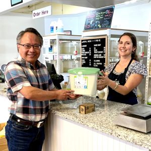 Woman handing a man a free compost pail over a counter in a store.