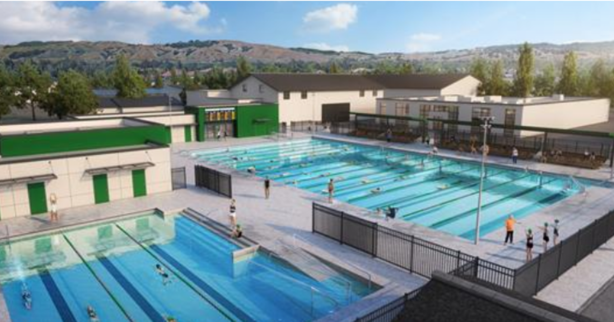 Two large pools with swimming lanes with a view of hills in background.