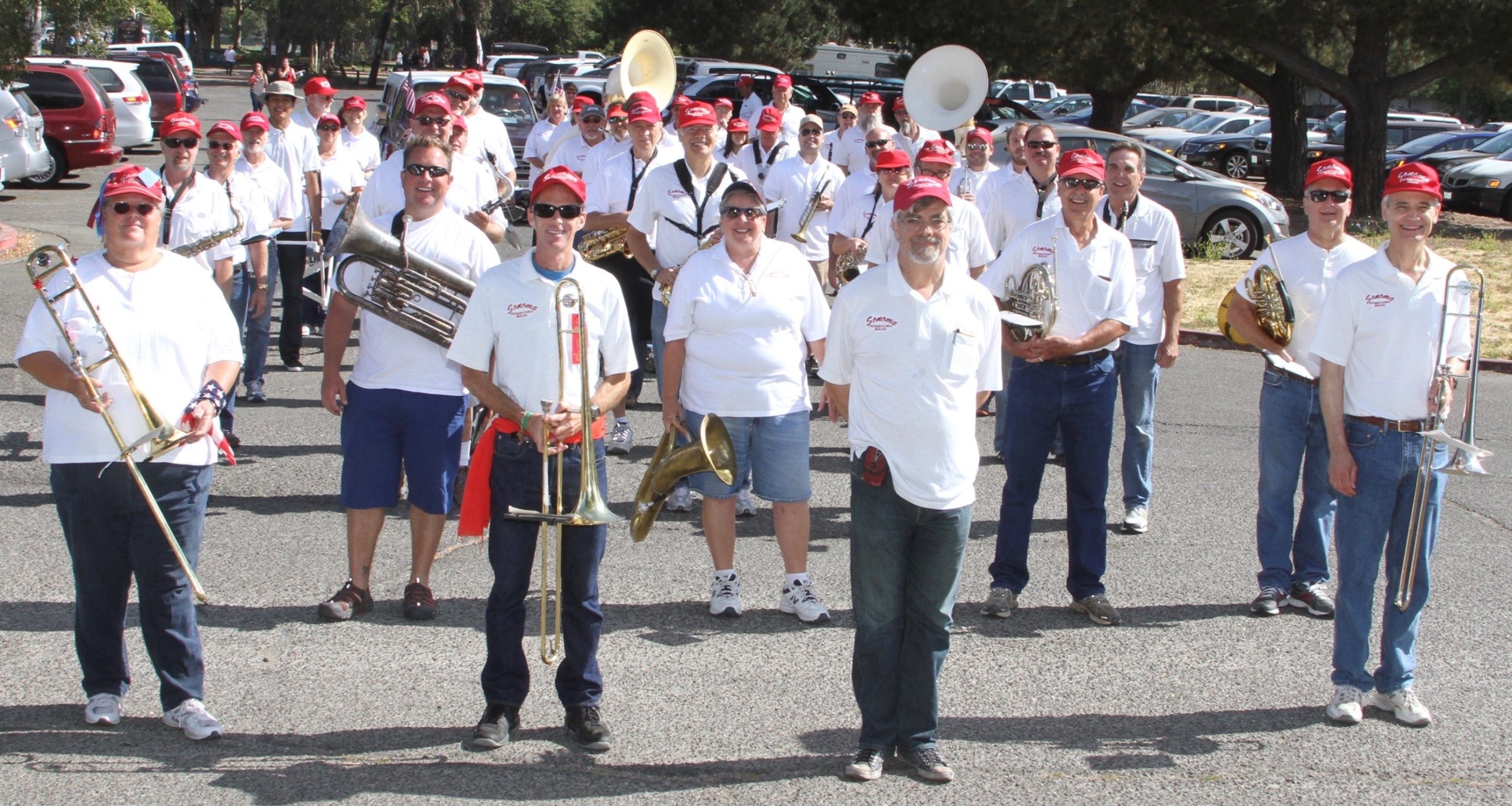 A marching band in red hats and white shirts lined up and facing the camera.