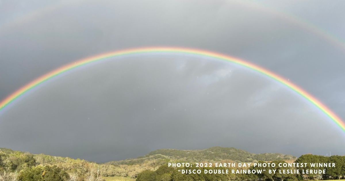 a double rainbow over hills and trees.