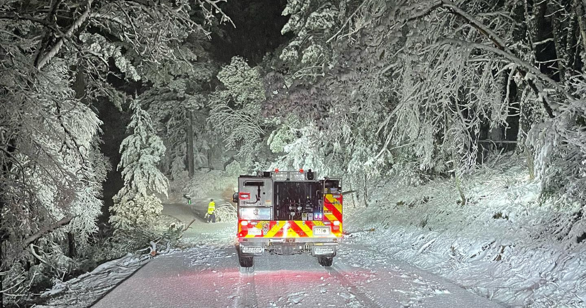 A fire truck parked on a snow covered road at night.