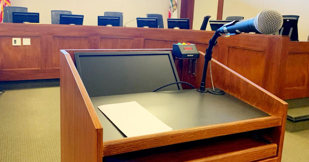 A close up photo of a podium and a microphone in front of a dias.