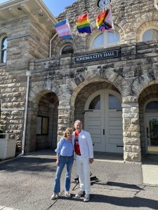 Mayor Lowe and Gary Saperstein in front of city hall with 3 pride flags.