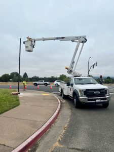 A cherry picker truck with a person in the bucket installing a light.