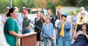 Ada Limon, 24th Poet Laureate of the United States, stands at a podium addressing a crowd during a bench dedication ceremony on August 18, 2023.