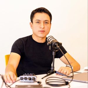 A photo of Victor Ferrer sitting at a table with a microphone.