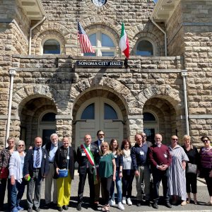 A group of people in front of the City of Sonoma City Hall displaying the American and Italian Flags.