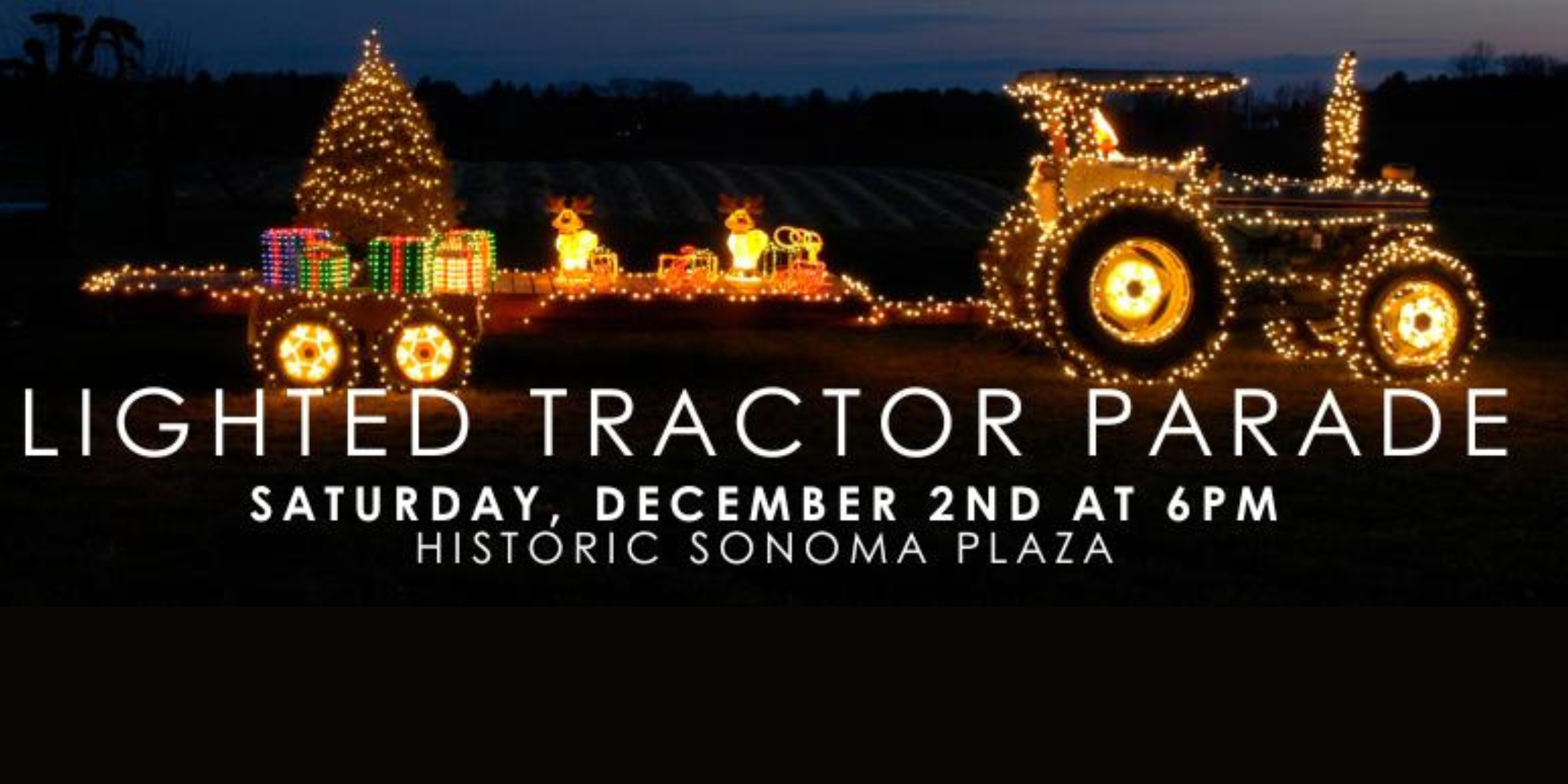 A photo of a tractor pulling a trailer with holiday paraphernalia and holiday lights.