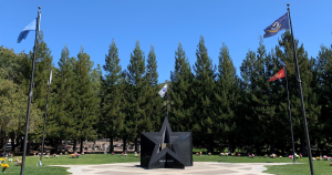 A sculpture of a large star surrounded by grass and flag poles.