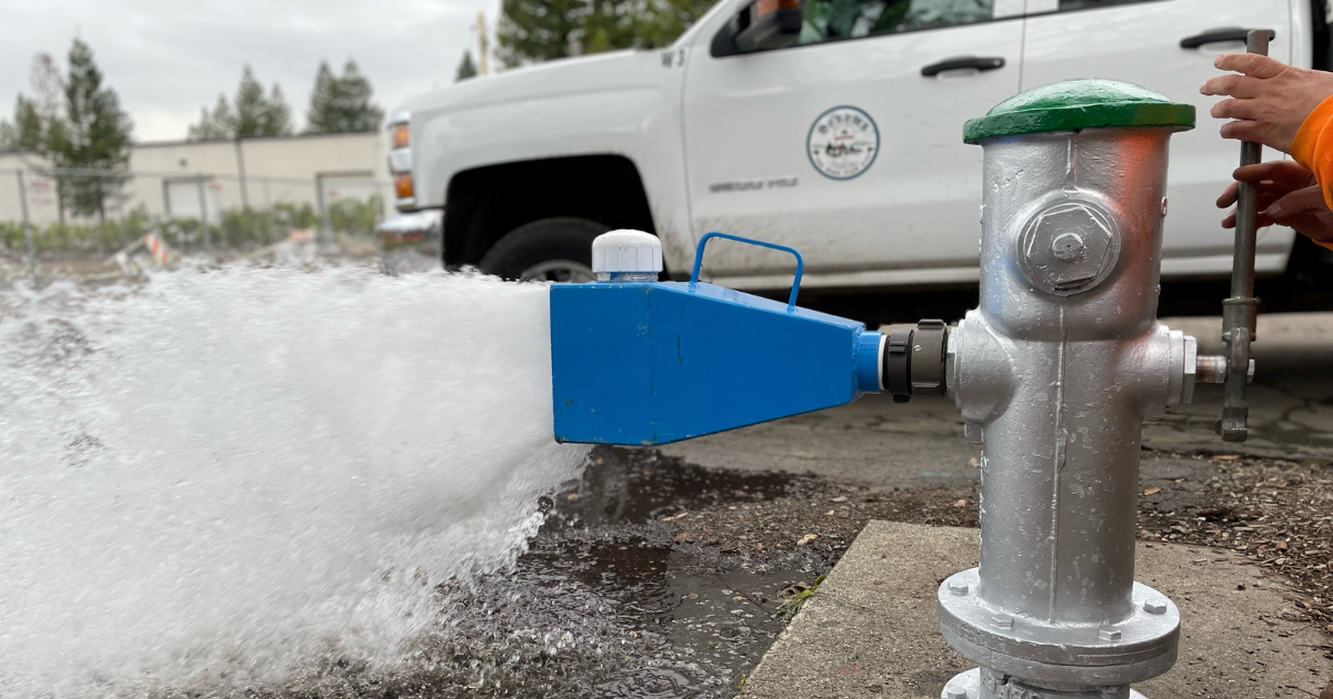 A water hydrant with a spout attached with water spraying out of the spout.