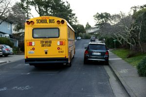 bus on a street, next to parked car