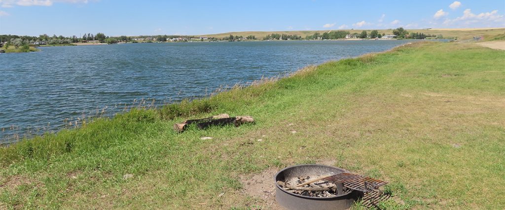 A campfire ring on the edge of a lake