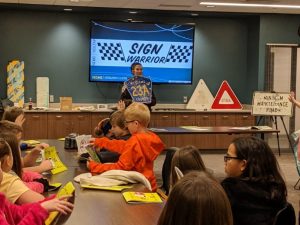 Female School Resource Deputy showing a vandalized sign to students