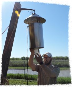 A man checking a New Jersey Light Trap for mosquitos