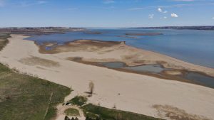 Aerial view of a lake with sandbars and rugged topography