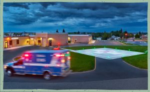 Ambulance with lights on driving past Tioga ER