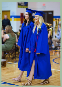Two girls walking in blue graduation cap and gowns