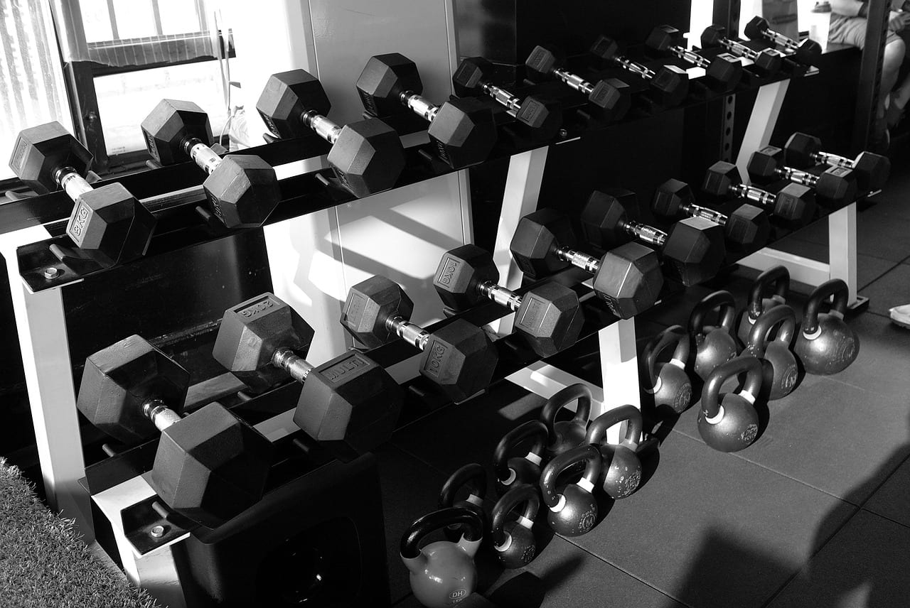 Row of rubber hex dumbbells arranged by weight on a steel rack
