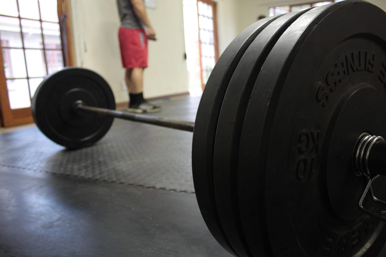 A flat workout bench set inside a sturdy power rack with a barbell