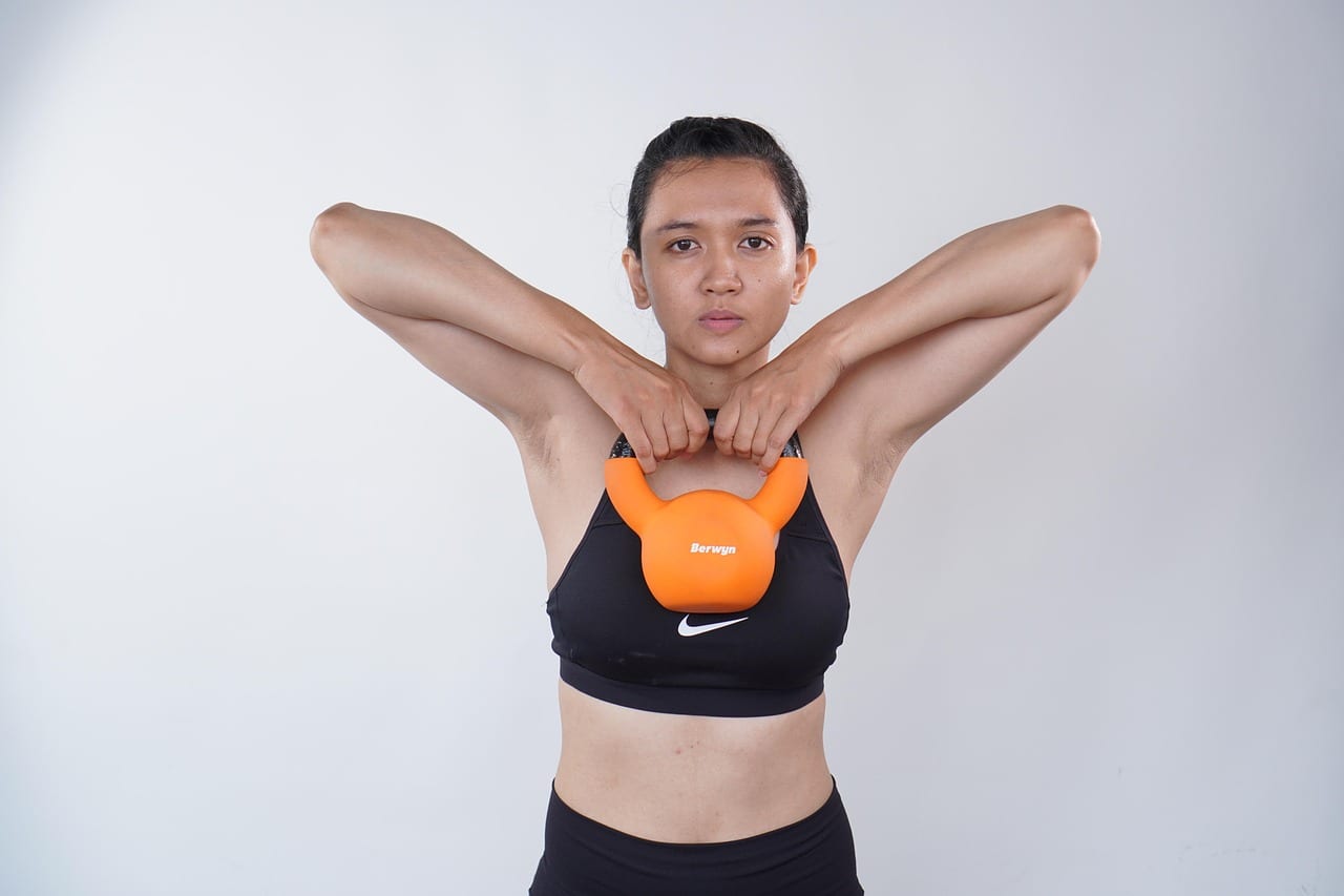 A person preparing to lift a kettlebell from the gym floor