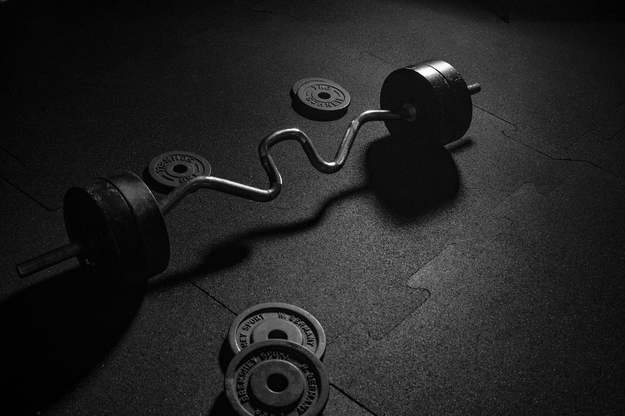 Heavy steel weight plates loaded on an Olympic barbell in a gym