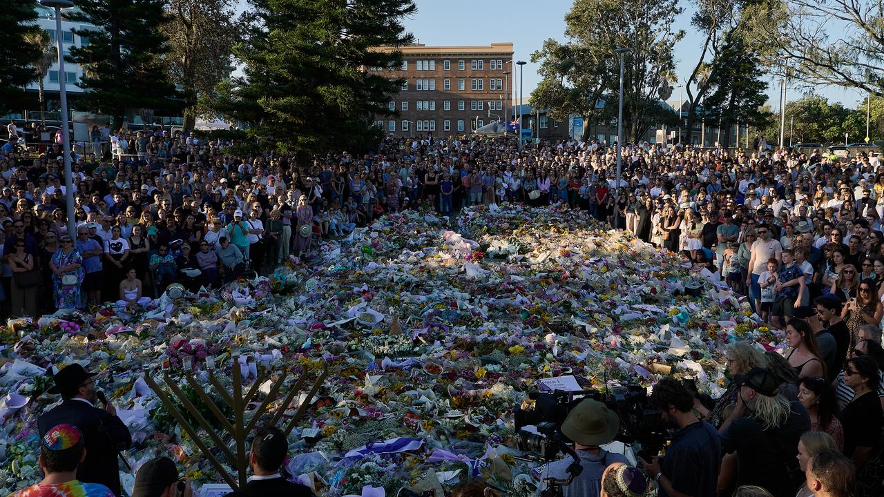 A crowd in front of a makeshift memorial at Bondi Beach.